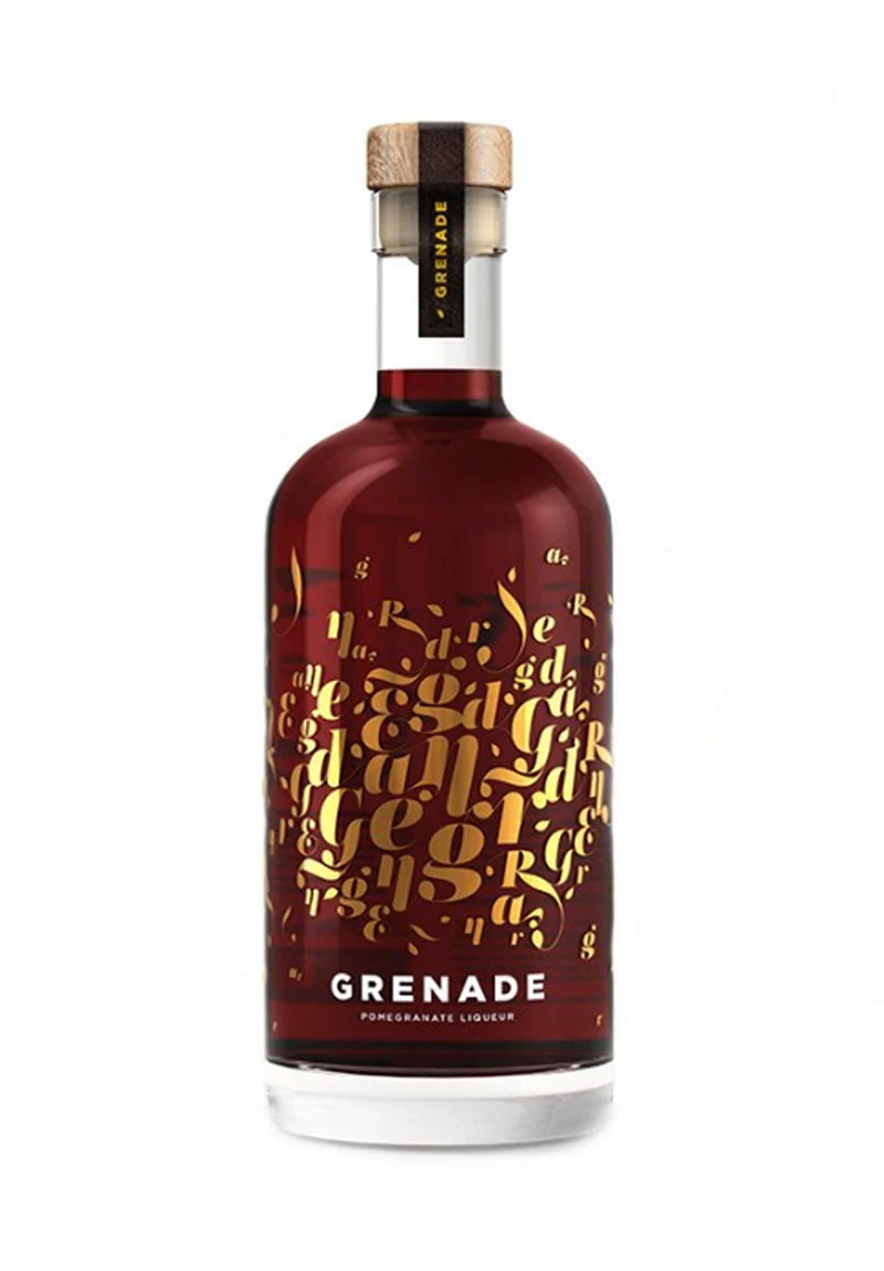 Eva-Distillery Liqueur Grenade. Grenade's fresh and explosive taste is reflected in its striking bottle, which displays a canvas of vintage gold letters forming the word Grenade against the natural background of the deep red liqueur.