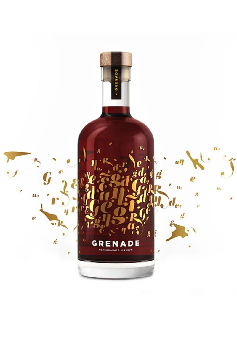 Eva-Distillery Liqueur Grenade. Grenade's fresh and explosive taste is reflected in its striking bottle, which displays a canvas of vintage gold letters forming the word Grenade against the natural background of the deep red liqueur.